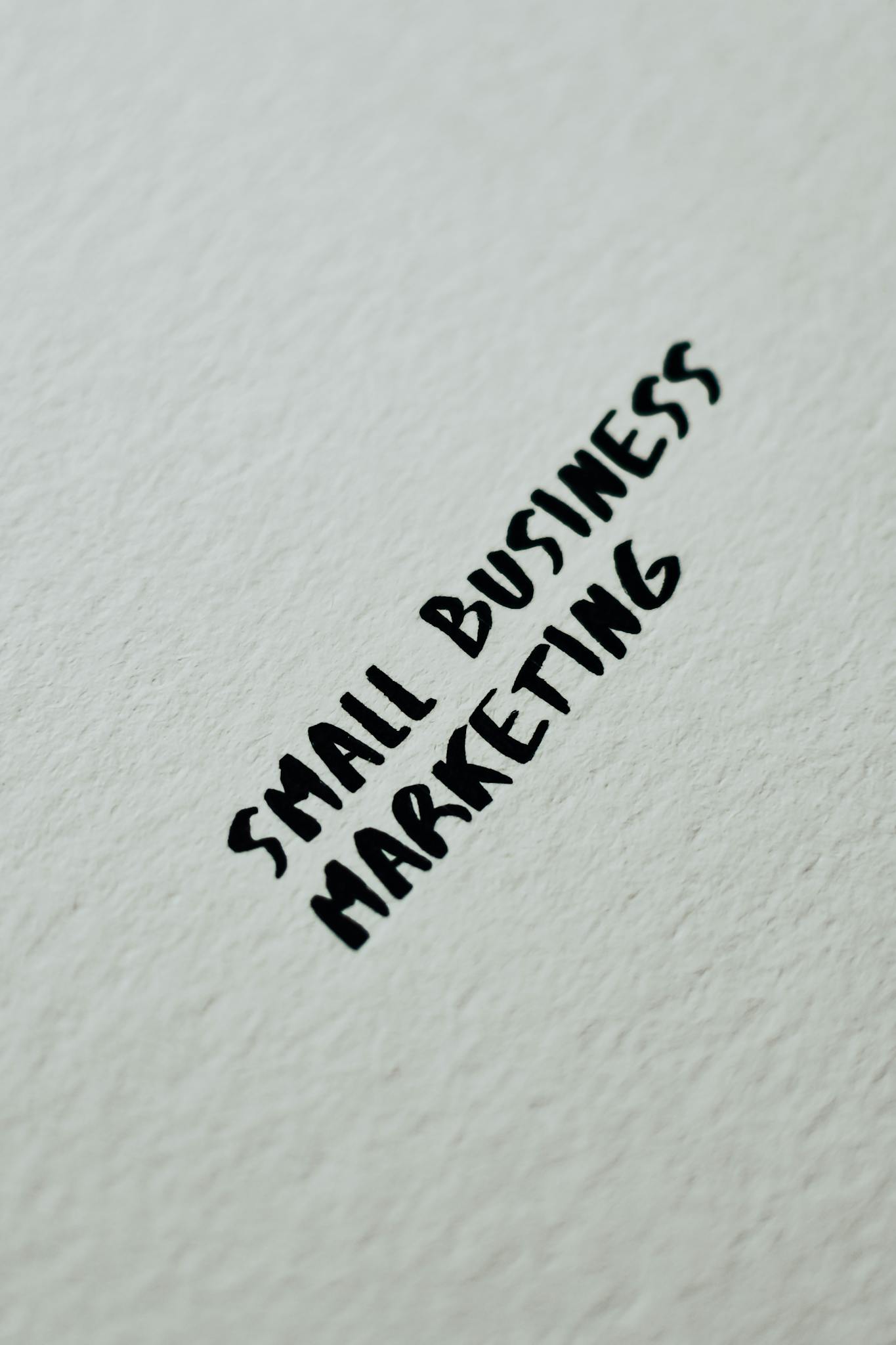 Close-up of small business marketing text handwritten on a white textured background for entrepreneurial themes.